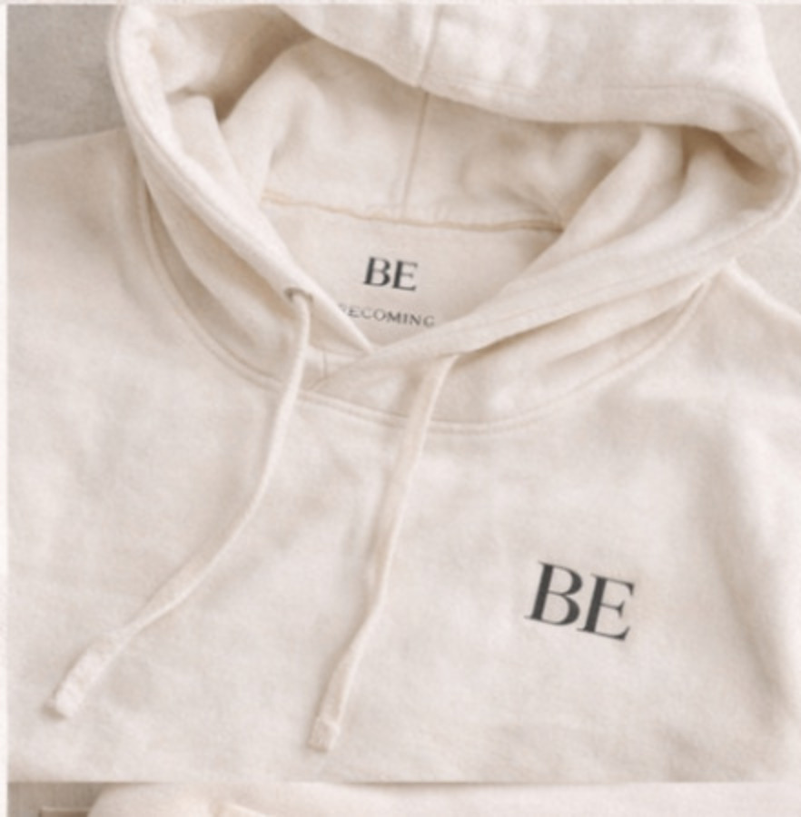 Cream hoodie study with a small embroidered BE chest mark